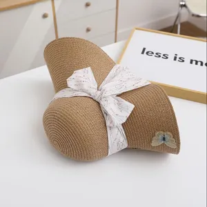 Detail shot of a stylish summer straw sun hat with floral ribbon bow and embroidery.
