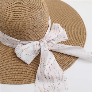 Close-up detail of a wide-brim straw sun hat featuring an elegant floral ribbon bow.