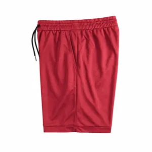 Red athletic shorts detail view, breathable fabric with black drawstring and side pockets.