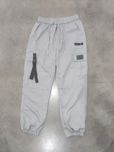 Detail view of grey mens loose cargo pants with drawstring and multiple pockets.
