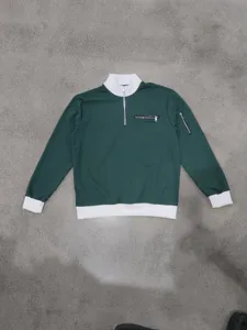 Dark green half-zip waffle sweatshirt detail, mock neck with ribbed cuffs and zipper pockets.