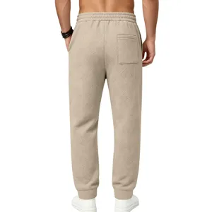 Detail view of men's textured casual sweatpants in beige, featuring a relaxed fit and back pocket.