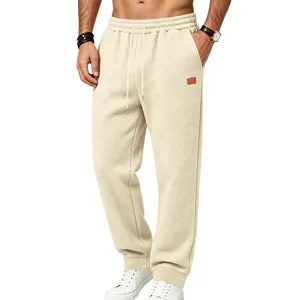 Detail shot of men's textured beige casual sweatpants showing relaxed fit and woven fabric.