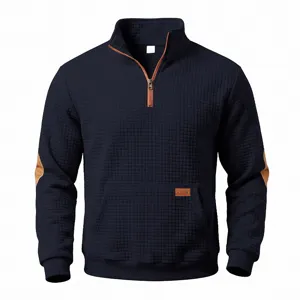 Close-up detail of the dark blue waffle-knit quarter-zip sweatshirt with brown leather accents.