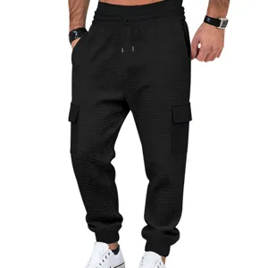 Vista detallada de los pantalones cargo negros de punto gofrado para hombre con bolsillos.