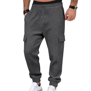 Detalle de textura de punto gofrado de pantalón cargo gris para hombre con bolsillos.