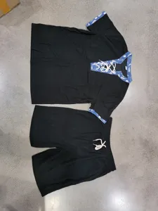 Close-up detail of the black corduroy short sleeve shirt and shorts set with blue paisley trim.