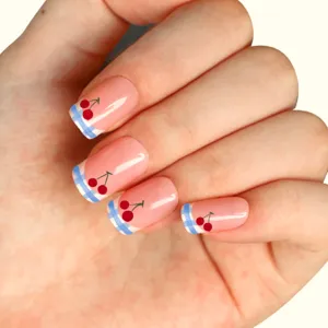 Detail shot of press-on fake nails featuring a blue and white plaid French tip and red cherry design.