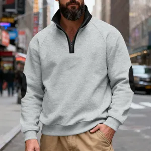 Detail shot of men's fleece quarter-zip sweatshirt with contrast elbow patches on street.