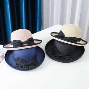 Vista detallada de sombreros de paja de verano para mujer apilados con lazos negros.