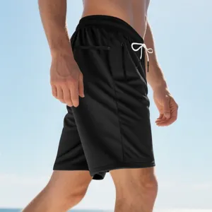 Schwarze Herren Sportshorts mit weissem Kordelzug und Reissverschlusstaschen am Strand.