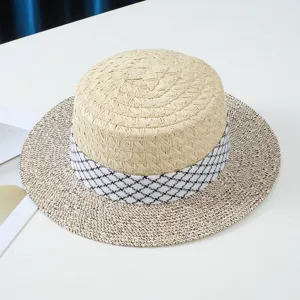Vista dettagliata dell'elegante cappello di paglia piatto da donna con nastro pied de poule.