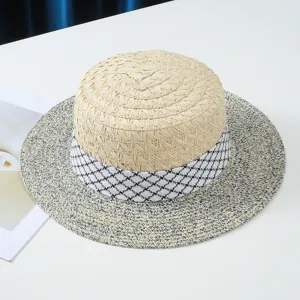 Primo piano del cappello di paglia estivo con nastro pied-de-poule e dettagli di tesa.