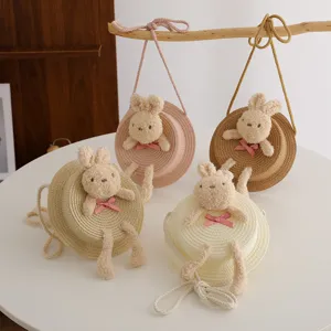 Borsa a tracolla rotonda in paglia per bambini con simpatico coniglietto di peluche e fiocco.