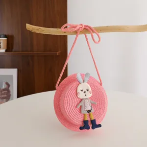 Children pink straw crossbody bag with cute rabbit plush detail, ideal for summer beach outfit.