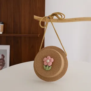 Borsa a tracolla rotonda in paglia per bambini con grazioso fiore in stoffa per vacanza.