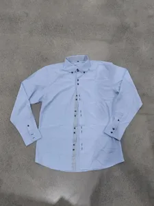 Detailed view of men's light blue long sleeve dress shirt with contrast print collar and buttons.