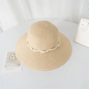 Dettaglio di un elegante cappello di paglia con perle e nastro, accessorio estivo per la spiaggia.