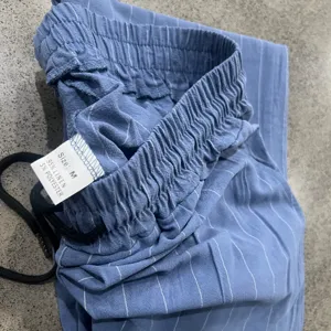 Detailed view of men's casual linen striped pants showcasing the elastic waistband and label.