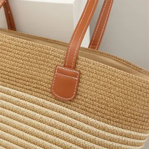 Detailed view of straw woven shoulder bag texture with brown leather strap and contrast stitch.