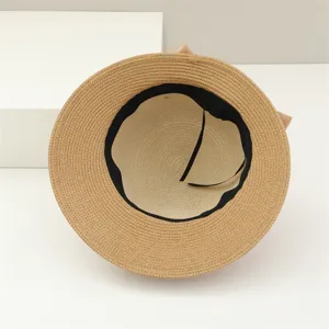 Cappello da sole in paglia intrecciata con fodera nera e fiocco per vacanze.