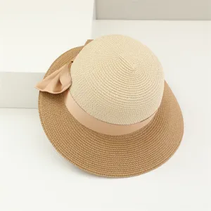 Primo piano di elegante cappello di paglia bicolore con nastro in satin per vacanze al mare.