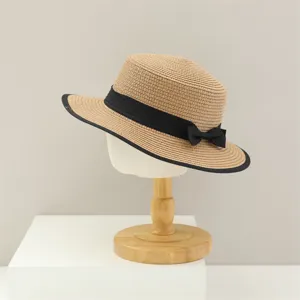 Vue de détail du chapeau de paille plat femme été avec nœud noir et bordure élégante.