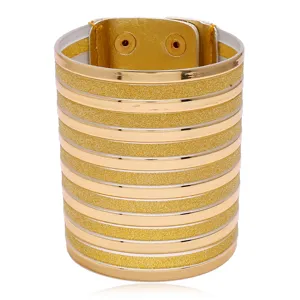 Detail view of a wide gold PU leather cuff bracelet featuring metallic stripes and snap buttons.