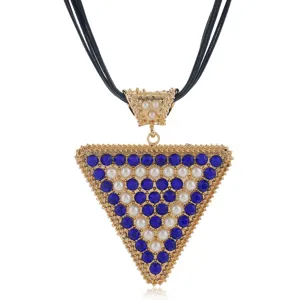 Detail view of the triangular pendant necklace with blue rhinestones and pearls on black cords.