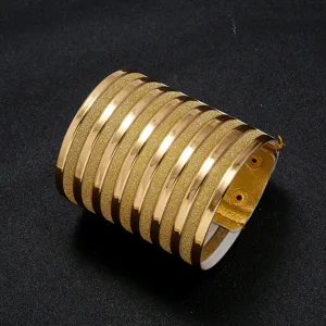 Wide gold PU leather cuff bracelet with metallic and glitter striped design detail.
