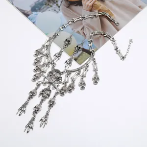 Detalle del collar colgante de calavera y huesos góticos, joyería de estilo punk plateado.