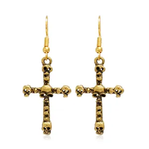 Primer plano detallado de pendientes de cruz de calavera de oro vintage estilo punk.