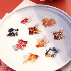 Dettaglio ravvicinato di ciondoli di pesce rosso in resina traslucida con stelle glitterate fai-da-te.