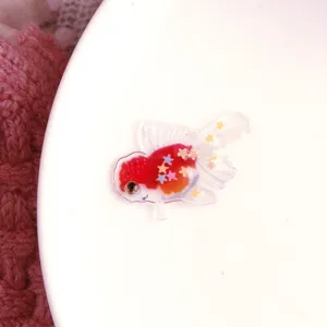 Primo piano dettaglio del ciondolo in resina con pesce rosso glitterato trasparente gioiello.