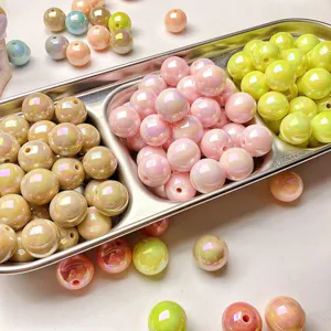 Close-up of glossy pastel resin round beads with iridescent finish in a metal tray.