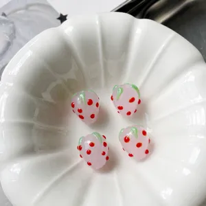 Close-up detail of handmade pink glass strawberry loose beads, 12x14mm DIY jewelry making.