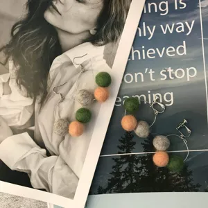 Gros plan détaillé de boucles d'oreilles boules de feutre colorées faites à la main.