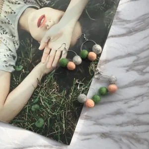 Gros plan détail de boucles d'oreilles créoles boules feutre colorées, mode automne.