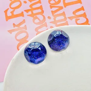Primo piano di cabochon in resina a mezza cupola blu scuro glitterati per le creazioni fai da te.