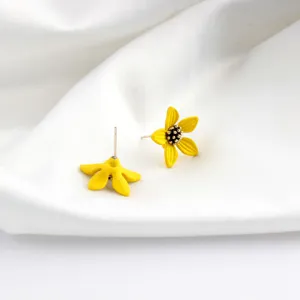 Detailed view of yellow flower stud earrings, painted floral design with metal pin, elegant accessory.