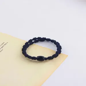 Detail view of a minimalist black elastic hair band with a chic cylindrical bead for daily styling.