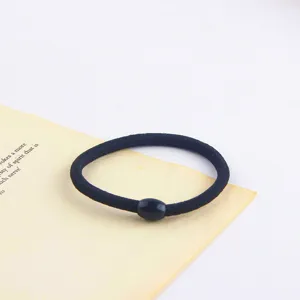 Close-up of a minimalist black hair tie with a small bead detail, simple and versatile.