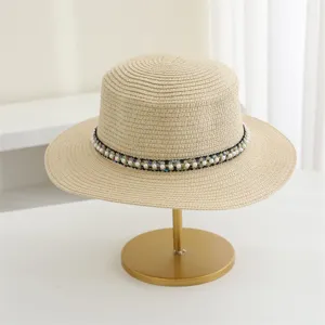 Gedetailleerd overzicht van beige strohoed met elegante parel gevlochten band, zomers.