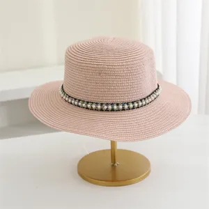 Roze strohoed met platte rand en stijlvolle parelband voor zomerse strandvakanties.