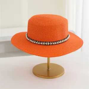 Elegante oranje strohoed met parelband voor dames, perfect voor het zomerse strand.