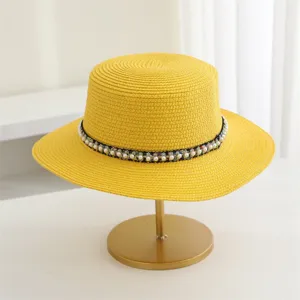 Detailopname van gele dames strohoed met platte rand en parellint, elegante stijl.