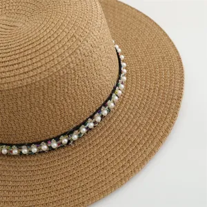 Detailopname van een chique dames strohoed met elegante parels en kleurrijke geweven band.