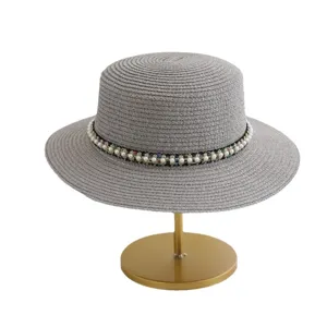 Zomer vrouwen grijze strohoed met elegante parel kralen band op gouden display standaard.