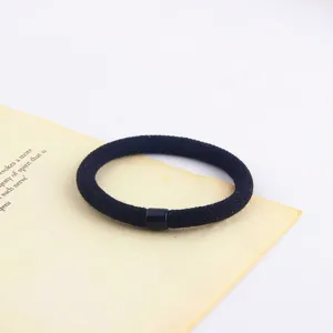 Close-up detail of the minimalist black hair tie featuring a sleek cylindrical bead and band.