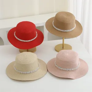 Detailansicht des flachen Strohhutes mit eleganter Perlenborte, breite Krempe fuer den Sommer.